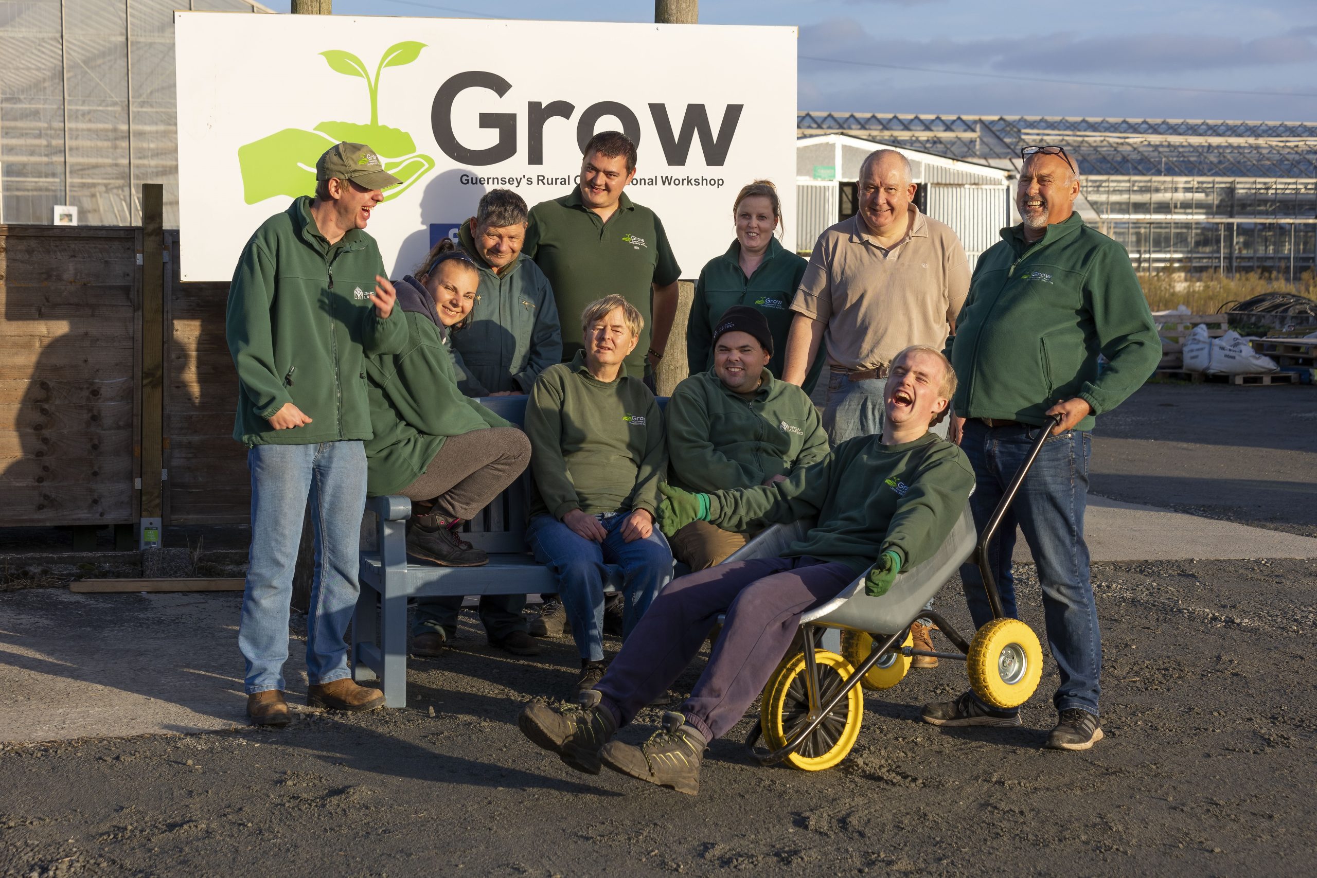 Volunteers from charity GROW sat on a bench posing in front of their sign