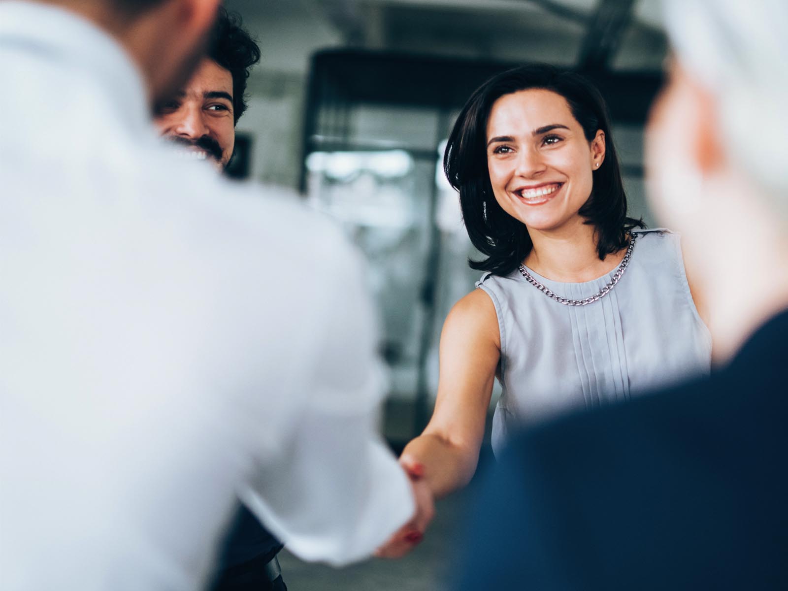 An image of a woman smiling while shaking a gentleman's hand