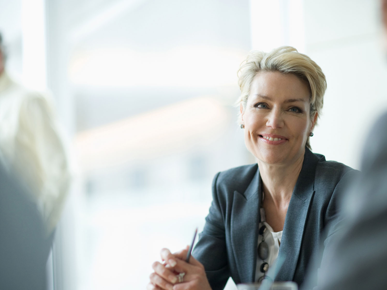 A blonde lady in a suit smiling at a colleague