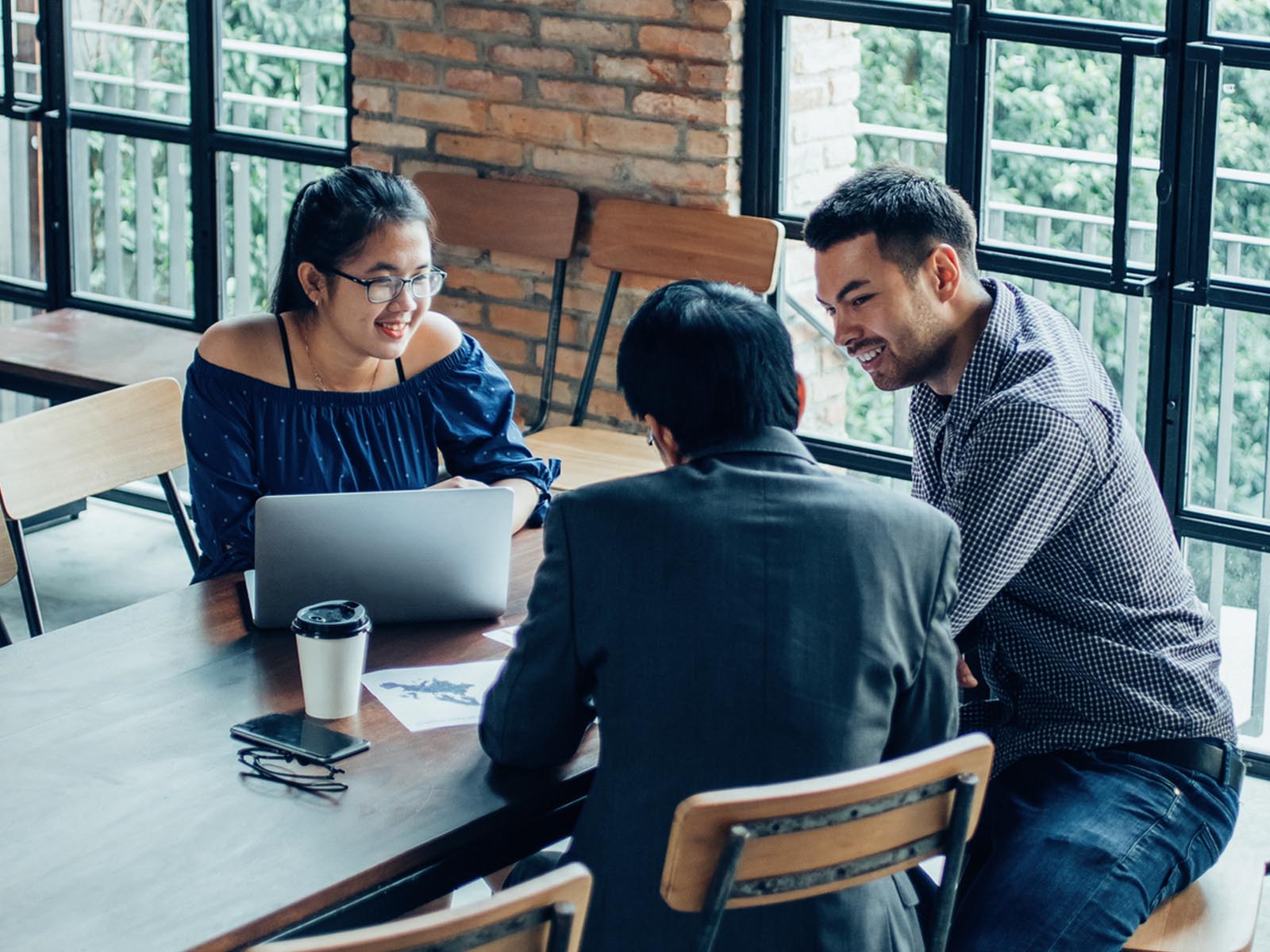 A group of three colleagues talking casually around a table