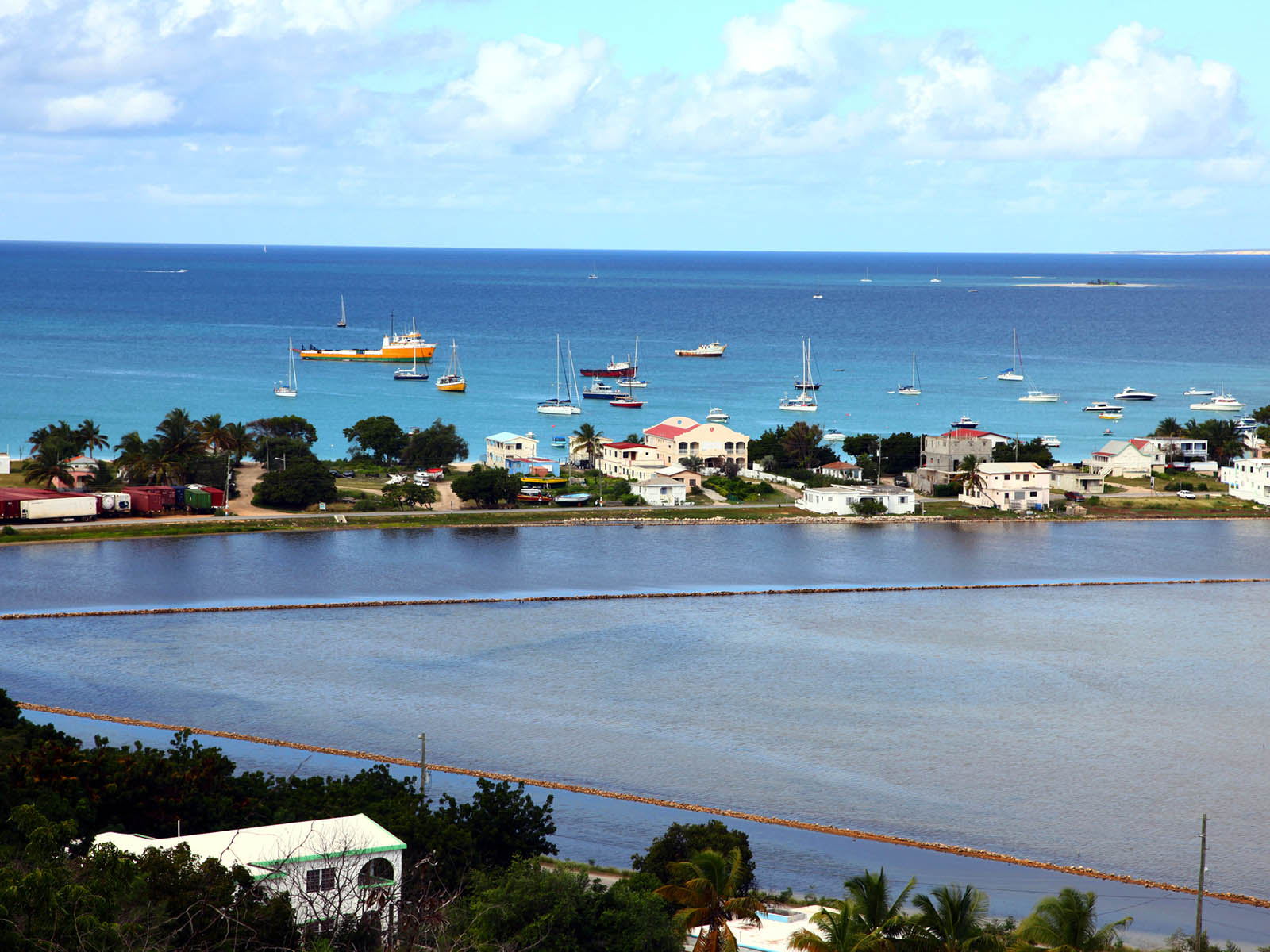 The sea with colourful boats. Houses on the coastline.