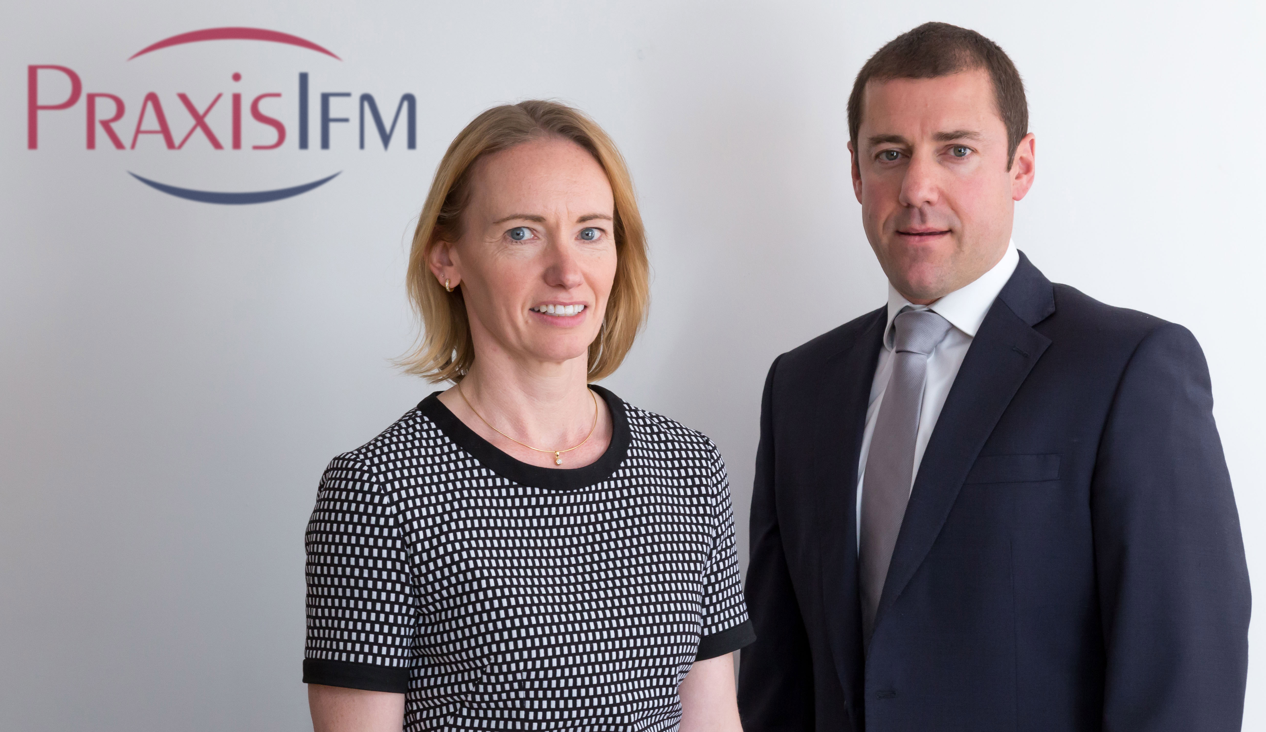 Lorna Morton and Shaun Robert posing in front of the PraxisIFM logo