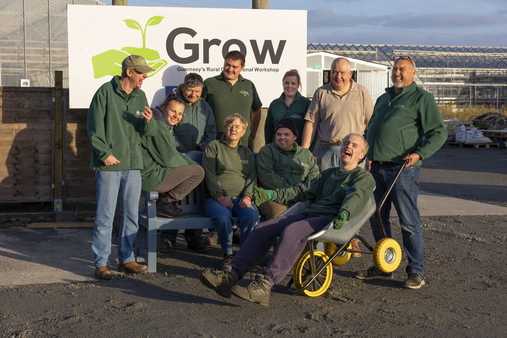 10 volunteers from charity 'Grow' sitting on a bench beside their sign